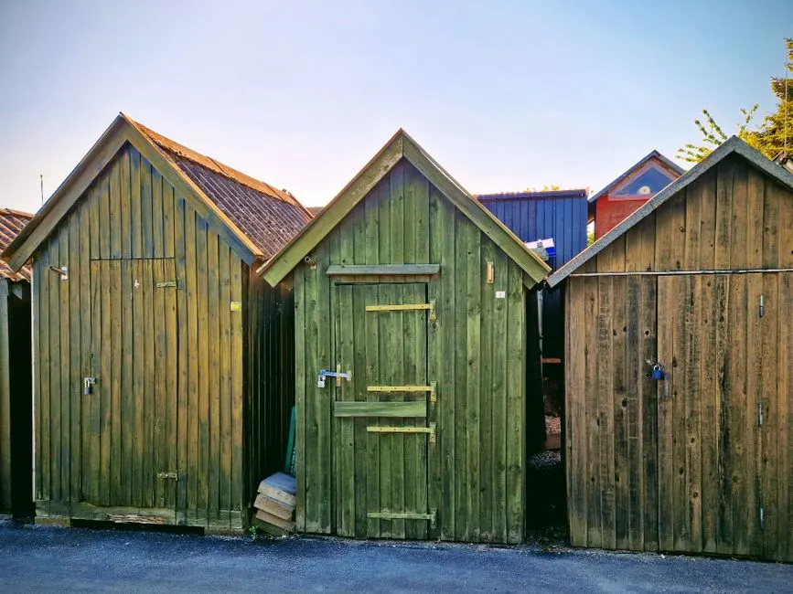Colorful wooden sheds in Assens, Denmark under clear summer sky.