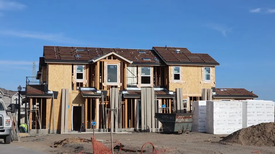 Front view of a two-story house under construction with clear blue skies.
