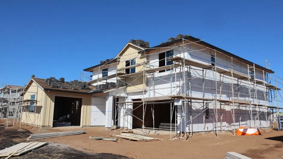 House under construction with scaffolding on a bright sunny day.